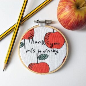 Embroidery hoop with red apple fabric and a thank you teacher quote