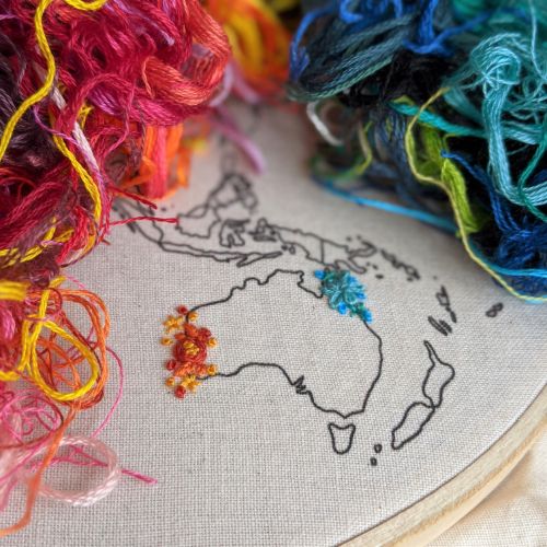 A close up of Australia with simple embroidery and a pile of threads