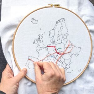 Hands stitching details to a map of Europe